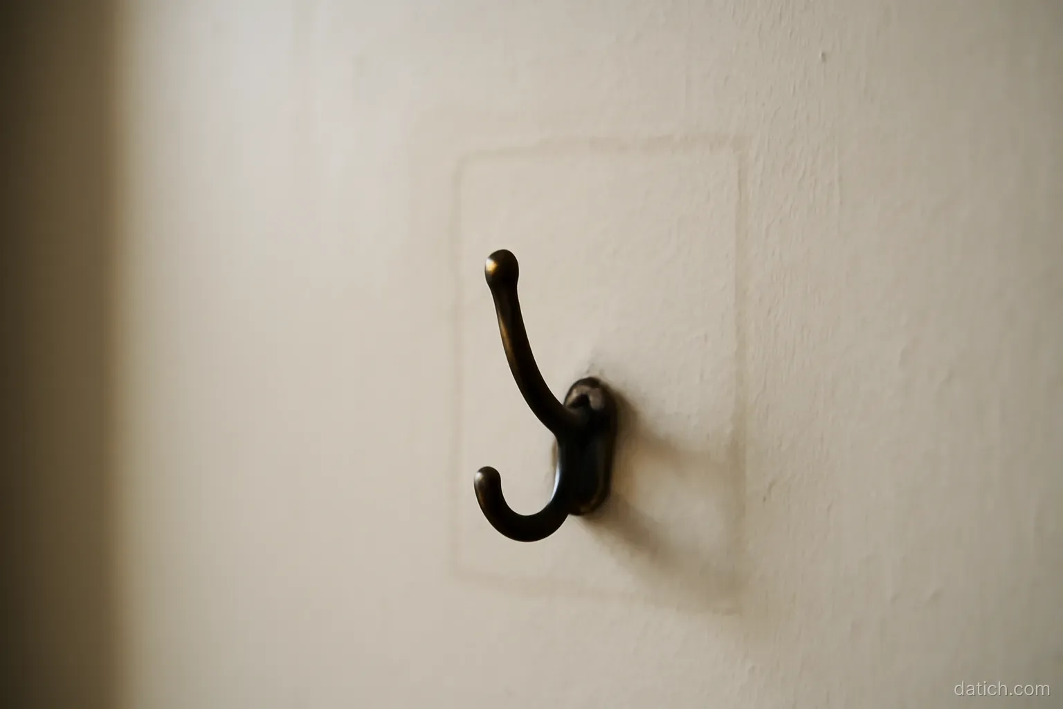 a bare hook on a wall where something used to hang, with a faint rectangular mark around it